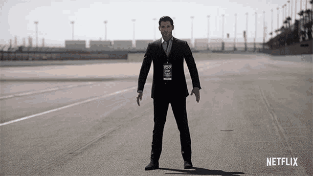 a man in a suit is standing on a road with a netflix logo behind him