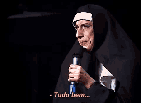 a woman dressed as a nun is holding a microphone and saying tudo bem .