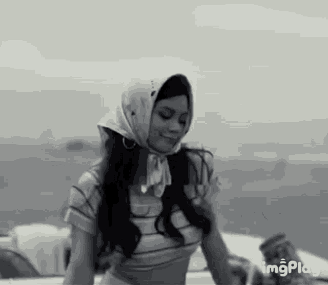 a woman wearing a scarf around her head is standing in front of a body of water .