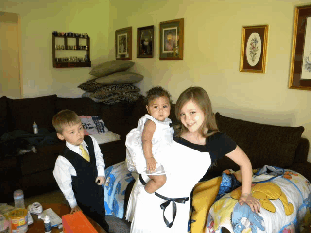a little girl in a white dress is being held by a girl in a black dress