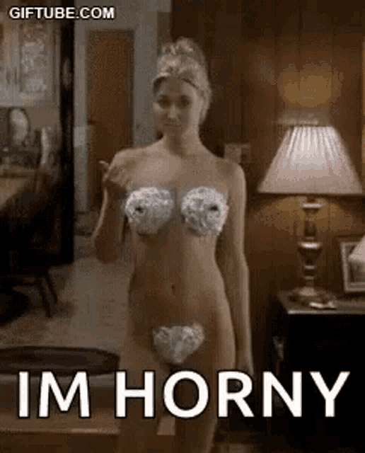 a naked woman in a bikini is standing in a living room with a lamp .