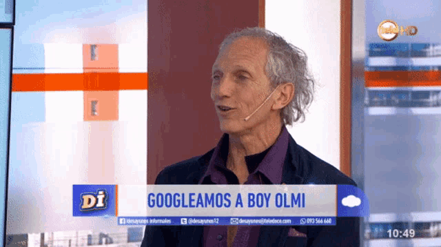 a man with a microphone stands in front of a sign that says googleamos a boy olmi on it