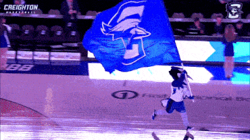 a cheerleader for the creighton basketball team holds a blue flag