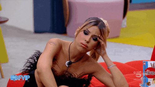 a woman sits on a red couch next to a box of massimo