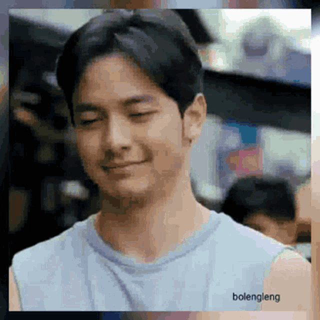 a man in a blue shirt is smiling with his eyes closed