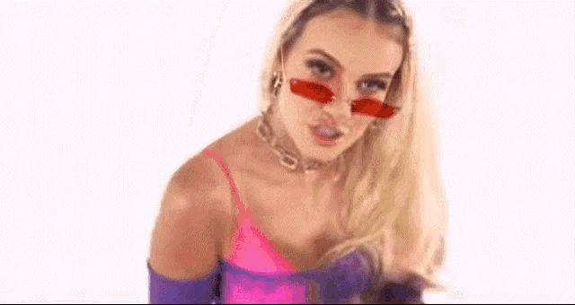 a blonde woman wearing red sunglasses is making a funny face .