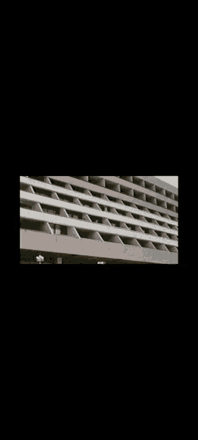 a black and white photo of a building with a row of balconies .