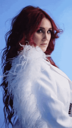 a woman with red hair is wearing a white coat with white feathers on the sleeves