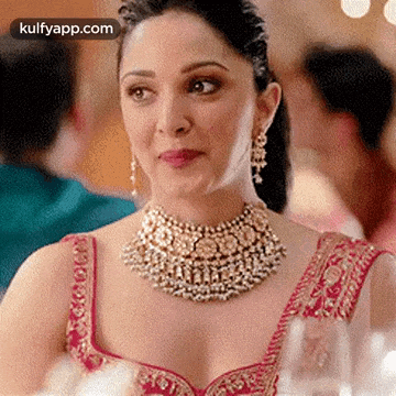 a woman is wearing a necklace and earrings and looking at the camera .