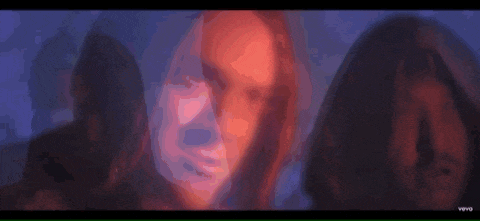 a man with long hair is standing next to a woman in a dark room