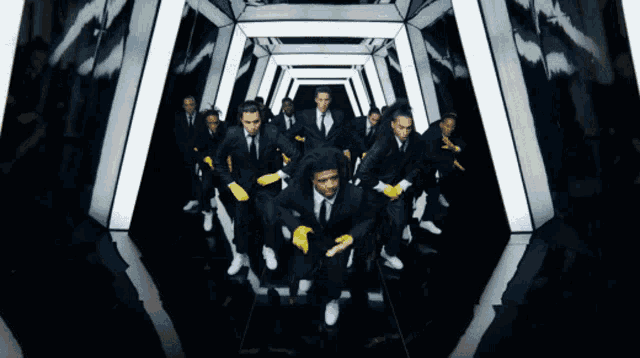 a bunch of men in suits and yellow gloves are running through a tunnel