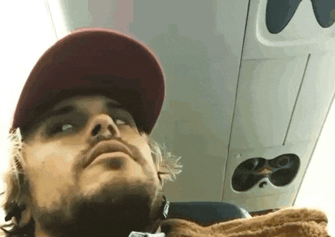 a man with a beard wearing a hat is sitting on an airplane