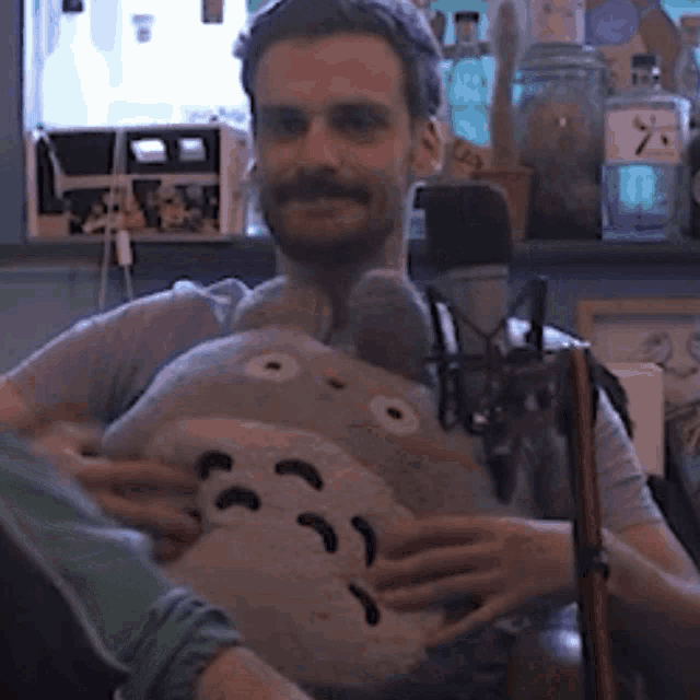 a man with a beard is holding a stuffed animal in his arms .