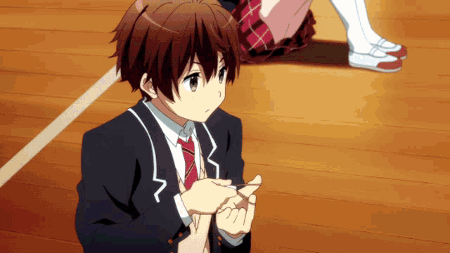 a boy in a suit and tie is sitting on the floor with his hands folded