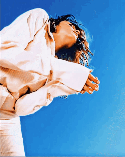 a woman in a white sweater is looking up at the sky