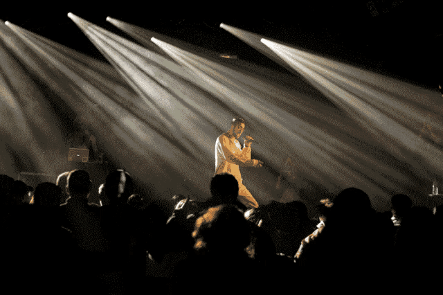 a man singing into a microphone in front of a crowd of people