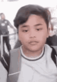 a young boy wearing a backpack is making a funny face .