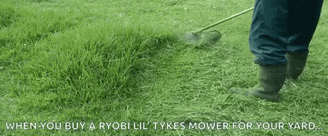 a person is using a ryobi lil tykes lawn mower to cut the grass
