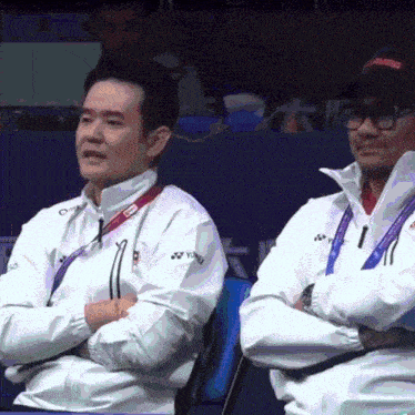two men wearing white jackets with yonex on them