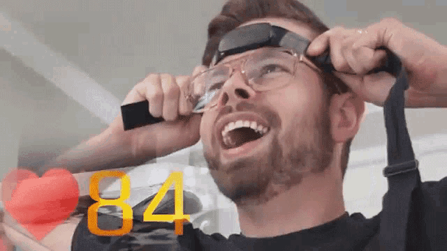 a man is wearing glasses and the number 84 is behind him