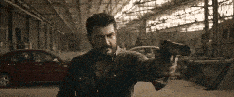 a man with a beard is holding a gun in a garage .