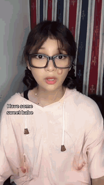 a girl wearing glasses and a pink shirt says " have some sweet babe "