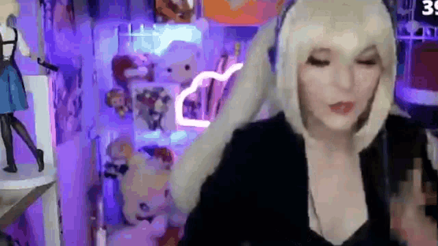 a woman is wearing a wig and headphones while playing a video game on a computer .