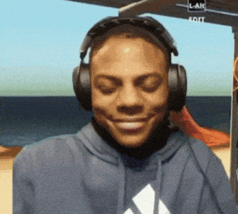 a man wearing headphones and a blue adidas sweatshirt smiles with his eyes closed
