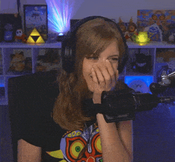 a woman wearing headphones is smiling in front of a microphone with a zelda poster behind her