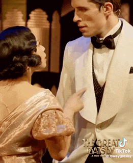a man in a tuxedo is pointing at a woman in a dress