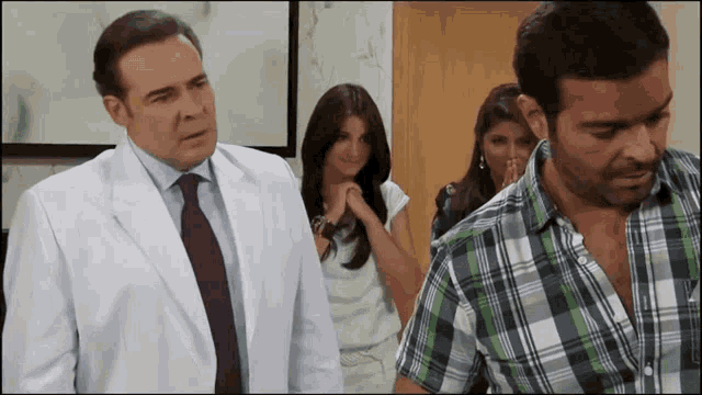 a man in a plaid shirt stands next to a man in a lab coat