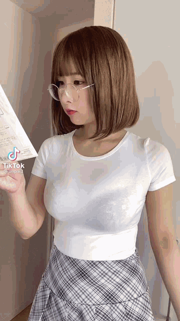 a woman wearing glasses is holding a piece of paper in her hand .