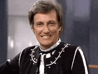 a man wearing a black and white outfit is smiling