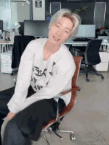 a man is sitting in an office chair with his legs crossed and smiling .
