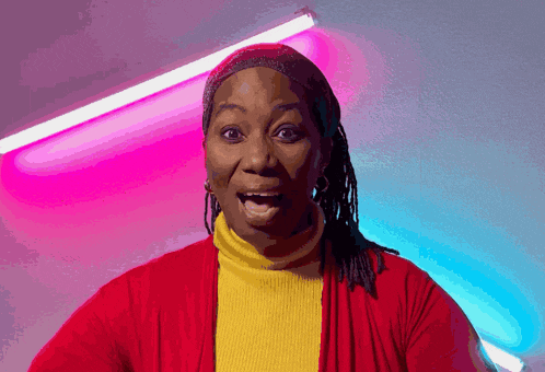 a woman wearing a red sweater and a yellow turtleneck has her mouth open