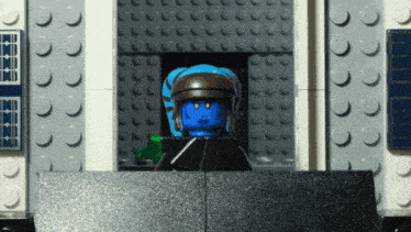 a lego figure with a blue head looks out of a window