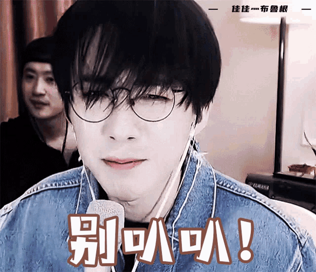 a man wearing a denim jacket and earbuds has a yamaha keyboard in the background