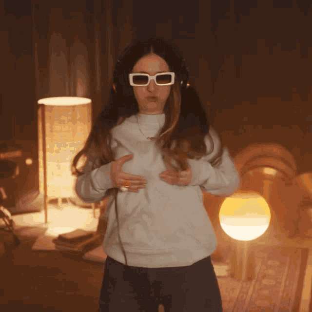 a woman wearing white sunglasses and headphones is dancing
