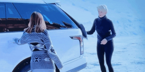 two women are standing next to a white suv