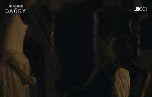 a woman in a white dress is standing next to a man in a dark room with the words jeanne barry on the bottom
