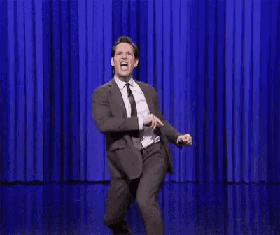 a man in a suit and tie is dancing on stage .
