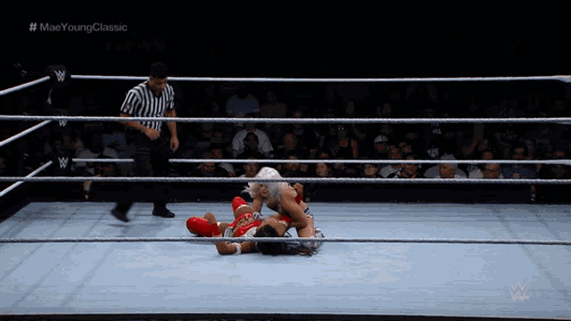 a wrestler is being pinned by another wrestler in a wrestling ring with a referee watching