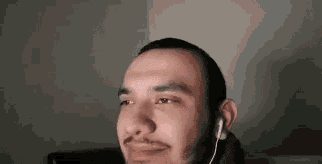 a man with a beard is wearing headphones and making a face .