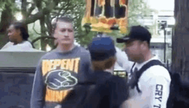 a man wearing a shirt that says `` independent '' is standing next to a man wearing a hat .