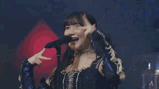 a woman is singing into a microphone with a choker around her neck