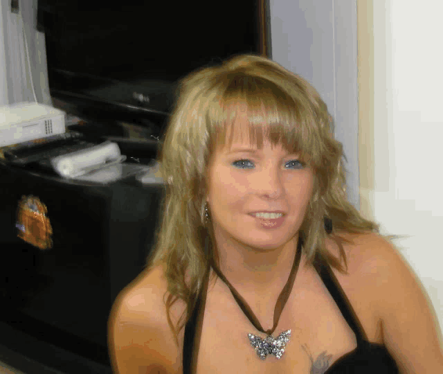 a woman wearing a necklace with a butterfly pendant