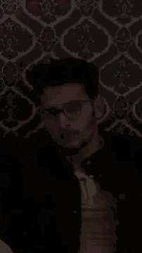 a man wearing glasses and a yellow shirt is giving the middle finger .