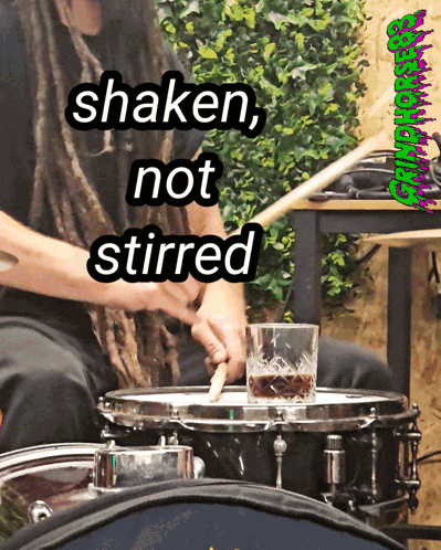 a man playing drums with a glass of whiskey on the drum set
