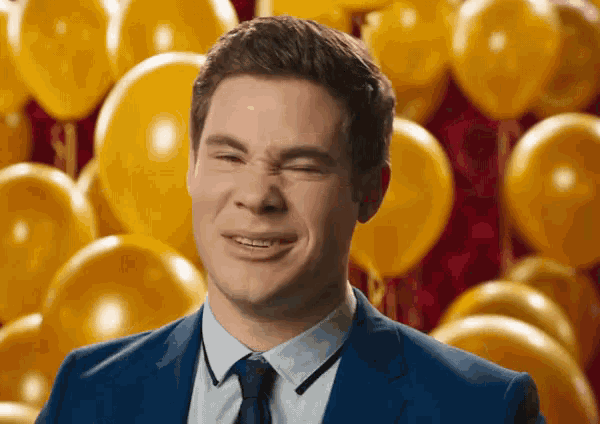 a man in a suit and tie is making a face in front of balloons