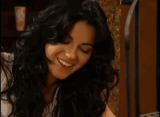 a woman with long black hair is eating a taco .